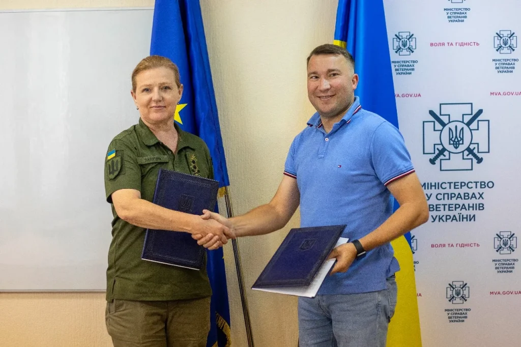 Наталія Калмикова та посадовець Мінветеранів обмінюються документами під час зустрічі