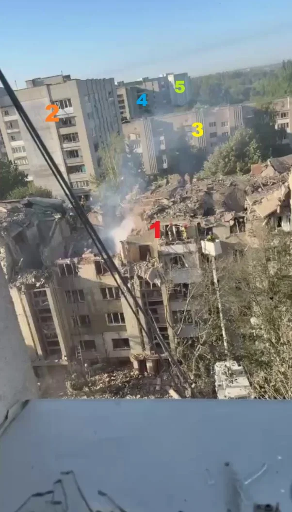 Зруйнований багатоквартирний будинок з димом серед інших житлових будинків