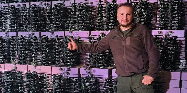 Сергій Бескрестнов демонструє FPV-дрон на тлі арсеналу для ударів