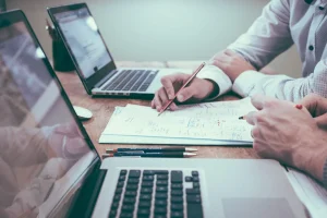 Колеги за столом з ноутбуками переглядають документи зі схемами