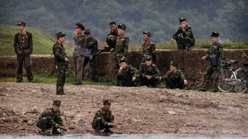 Військові в камуфляжі та формі біля річки на тлі зелених пагорбів