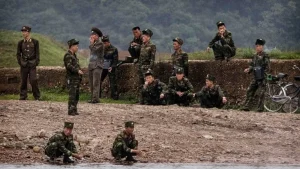 Військові в камуфляжі та формі біля річки на тлі зелених пагорбів