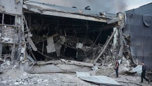Зруйнований склад із димом і двоє чоловіків серед уламків