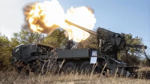 Колісна самохідна гаубиця стріляє потужним спалахом серед сухої трави
